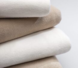 Stack of the Snow Storm blankets in ivory and tan. These are 100% polyester blankets.