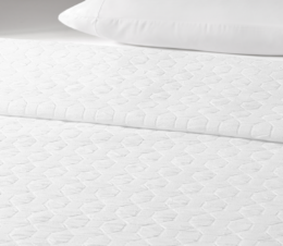 An Ellis Square top cover placed atop a luxurious hotel bed.