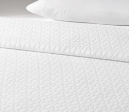 A stylish Quinn Top Cover decorates a hotel bed with a fresh, symmetrical pattern.