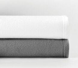 Shown stacked are the Express by Standard Textile fleece blankets in White and Grey.