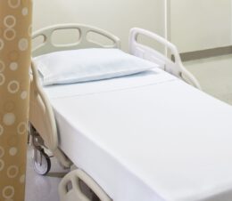 Excel® Hospital Sheeting for hospitals and health systems. Shown here on a hospital bed. Available in flat sheet, pillowcase, contour sheet, or draw sheet.