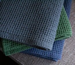 Stack of three Honeycomb Waffle Throw blankets in Charcoal, Denium and Evergreen.