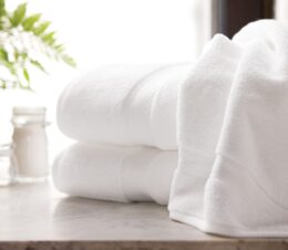 Two artfully arranged towels on a marble countertop with sunlight coming through a window in the background. The Lynova brand towel are microcotton towels.