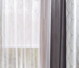 Shown here is a custom drapery project with sheers with textural vertical stripes and drapes with a hexagon pattern in ivory taupe and grey.