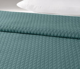 The Keaton bedspread in Storm is shown on a bed.