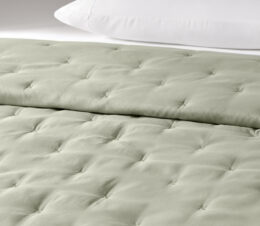 The Casa quilted bedspread shown here on a bed. This reversible bedspread is shown here in Eucalyptus.