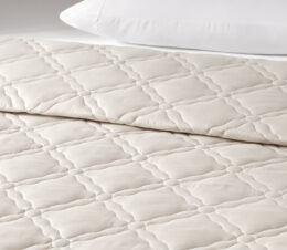 The lattice quilted Chateau bedspread is shown here on a bed in the Birch colorway.